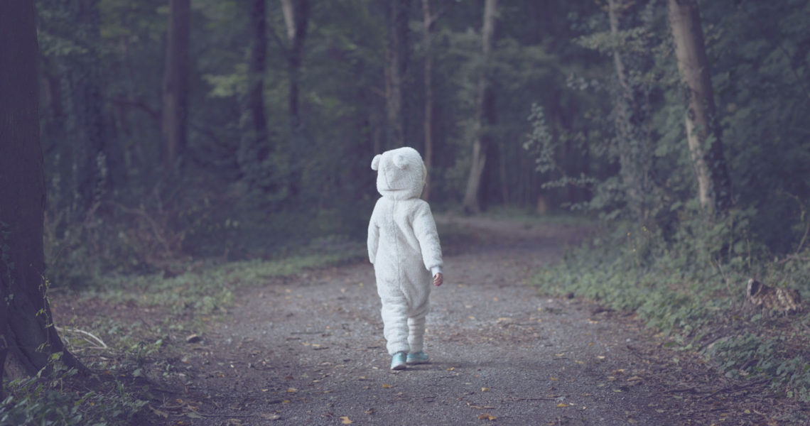 child in forest wearing bear suit